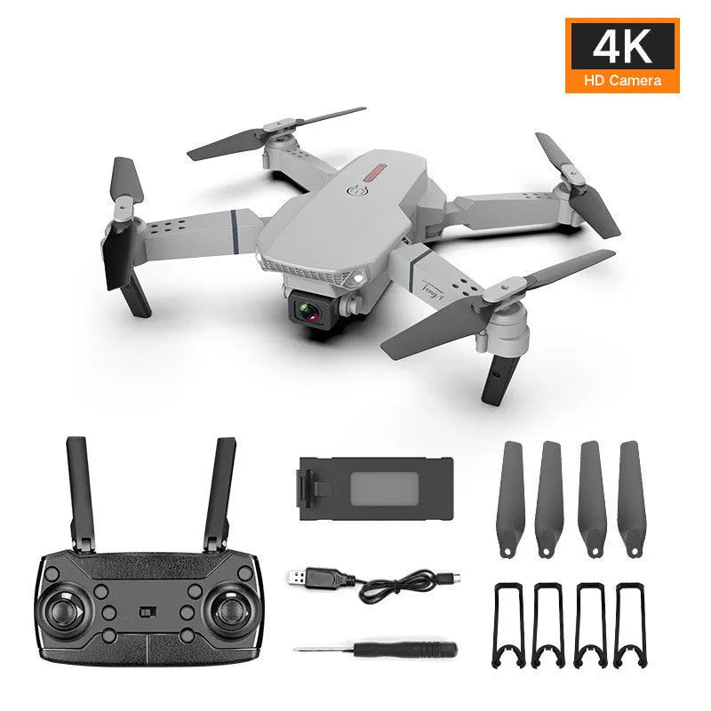 Grey foldable 4K aerial drone with dual cameras and remote control on a grassy field.