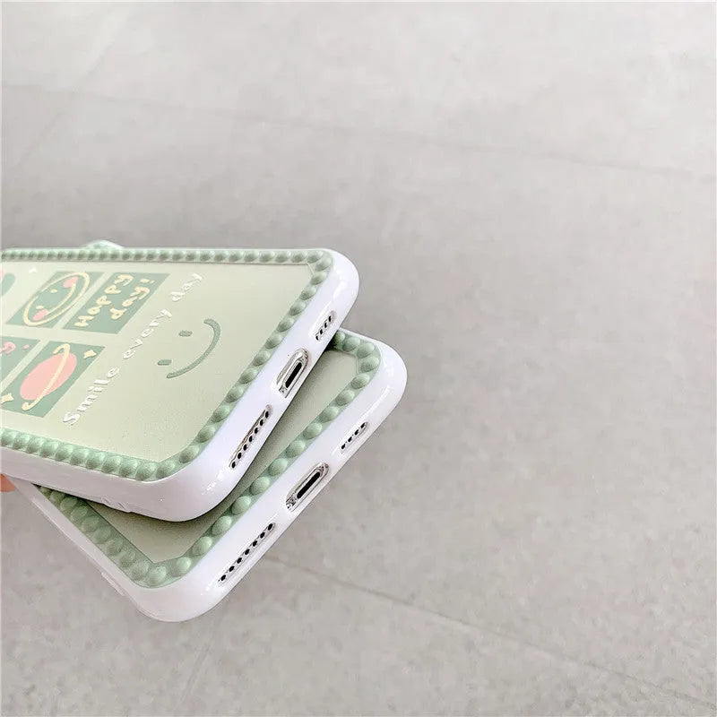 Green TPU iPhone case with geometric smiley face and polka dot frame designs on a table