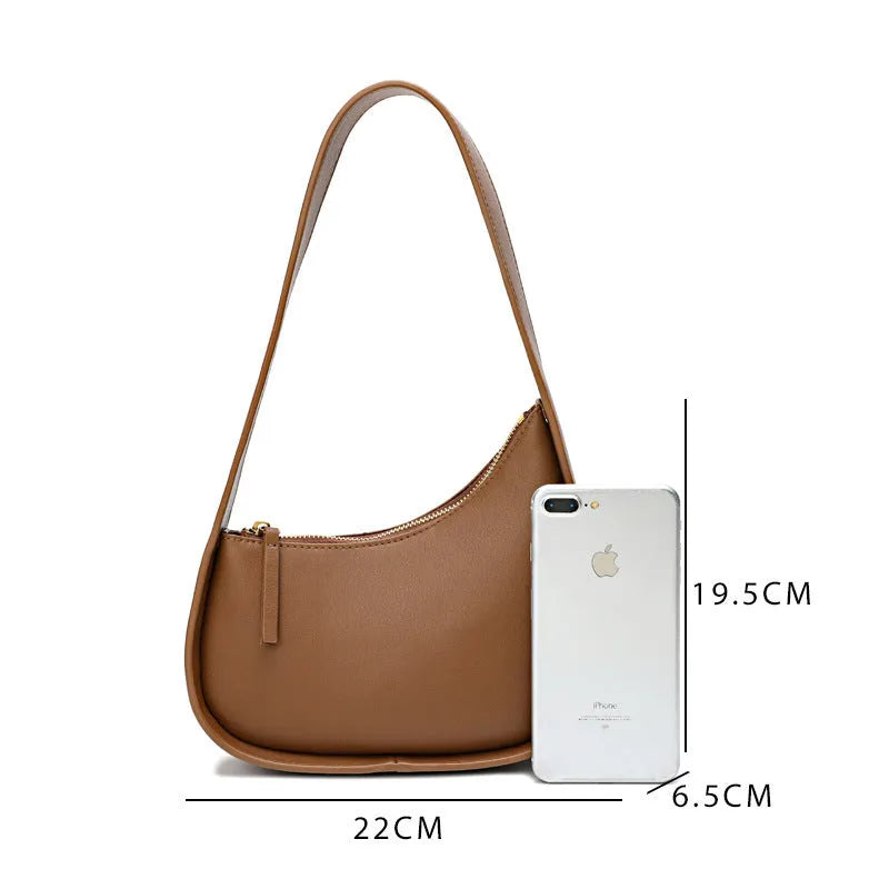 Leather ladies handbag in half-moon shape with wide shoulder strap and zipper opening