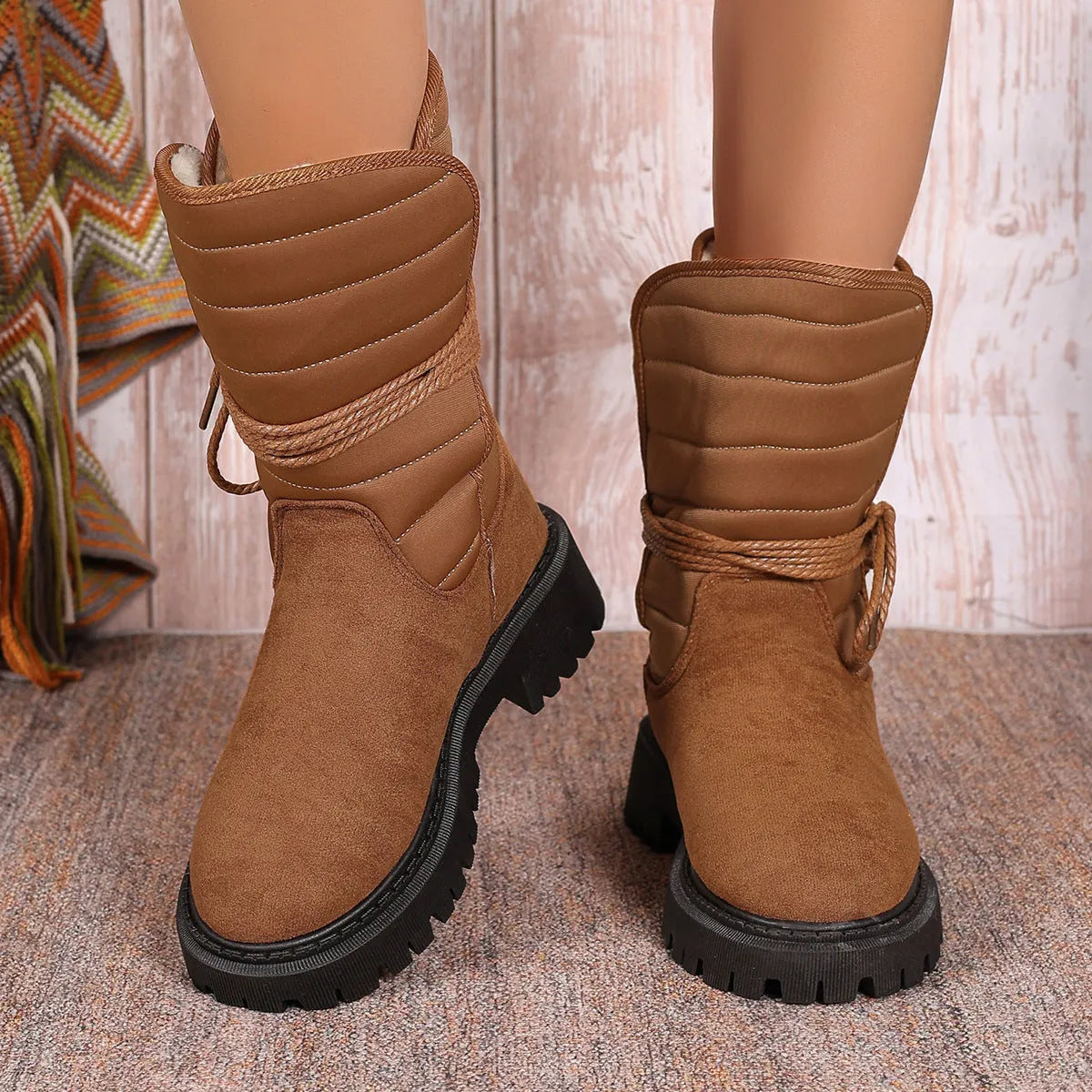 Women's black chunky heel snow boots with suede upper, rubber sole, and lace-up design on wooden floor