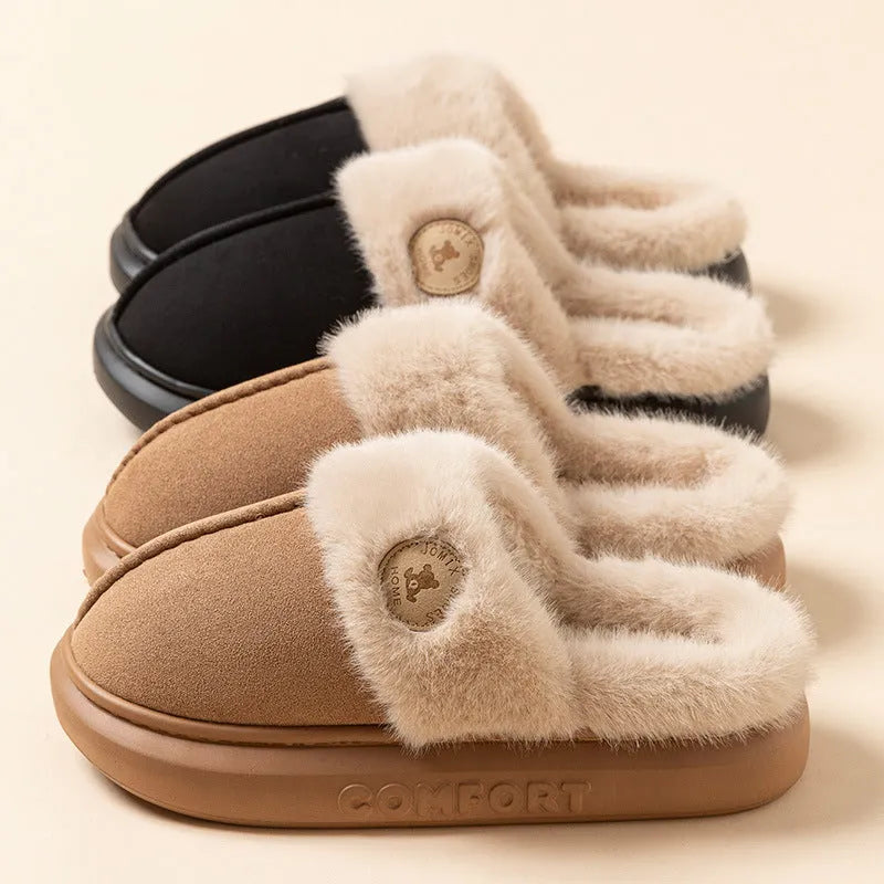 Plush slippers in black with fleece lining and non-slip PVC soles, shown on a wooden floor