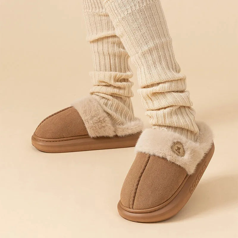 Plush slippers in black with fleece lining and non-slip PVC soles, shown on a wooden floor