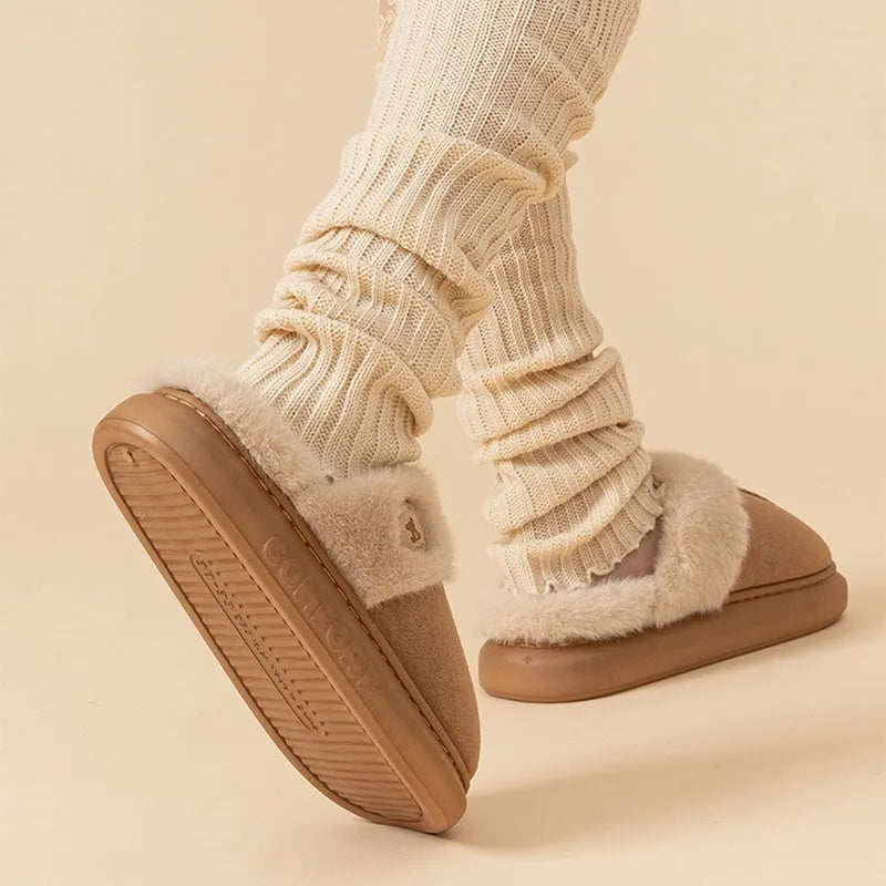 Plush slippers in black with fleece lining and non-slip PVC soles, shown on a wooden floor