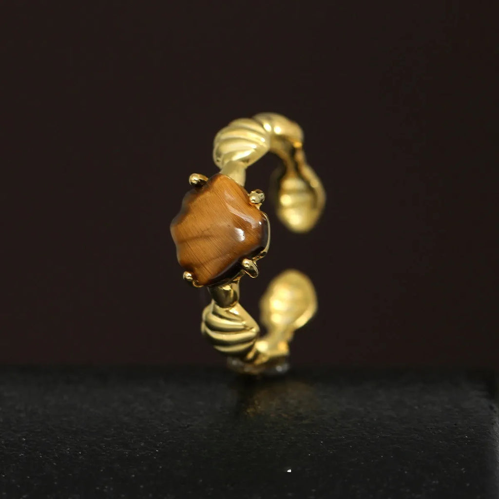 Adjustable silver ring with shell and tiger eye accents in gold electroplated finish showing opening mechanism