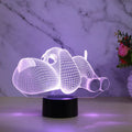 Doggo shaped 3D illusion desktop lamp glowing in multiple colours on a desk.