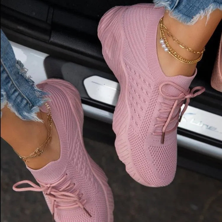 Women's white thick-sole dad sneakers on a plain background, showing the chunky sports shoe design.