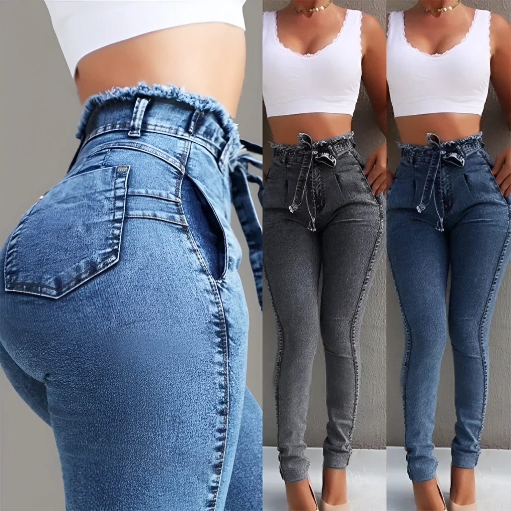 A pair of light blue fringed jeans with a distressed hem laid flat.