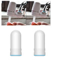 White plastic faucet water filter with universal adapter kit and ceramic cartridge on a kitchen tap.
