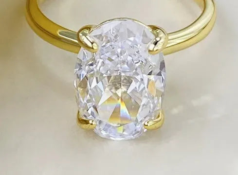 Oval women's ring in 9 silver with four-claw setting holding a 6x9mm gemstone, shown in gold and silver finishes.