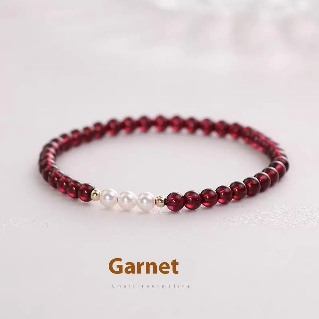 Close-up of a women's adjustable crystal bracelet with red garnet and white artificial pearl beads.