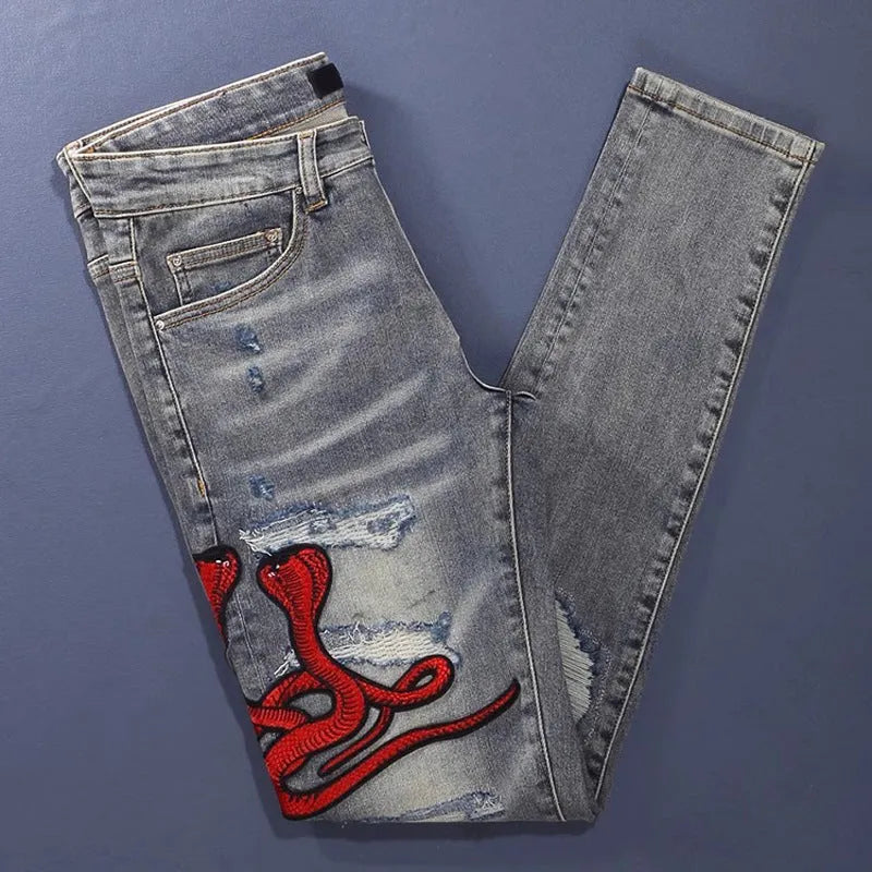 Men's slim fit distressed jeans with embroidered patches in an old colour wash.