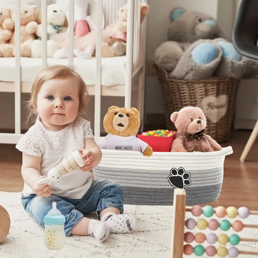 Small woven cotton rope storage basket with wooden handle in light beige, measuring 34x26x15cm, on a shelf with toys