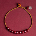 Hand-woven bracelet made from raw cinnabar and Hetian jade beads in a geometric design.