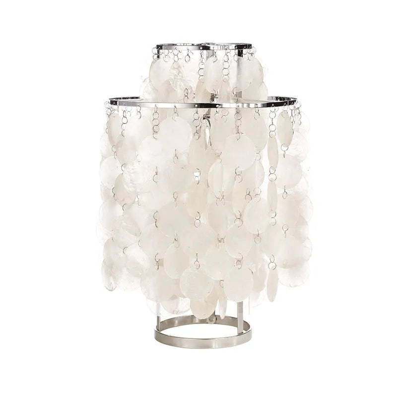 Modern shell-shaped bedside table lamp in a chrome finish on a wooden surface.