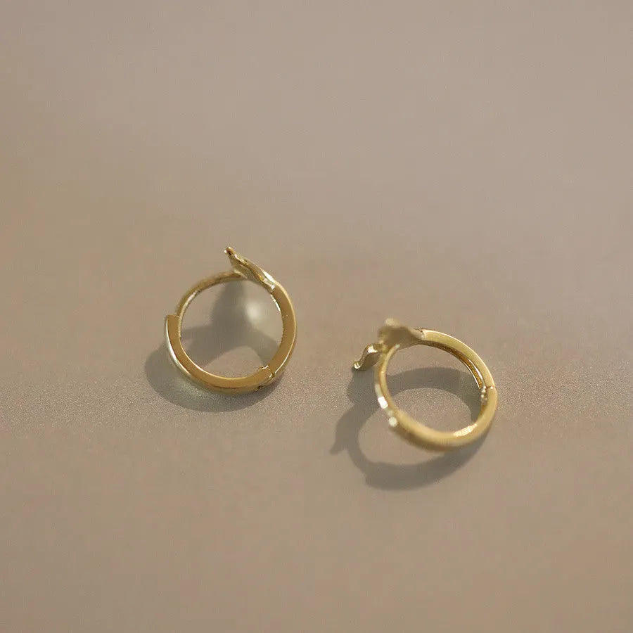 Pair of smooth fishtail earrings in gold or white gold plating, made from 925 sterling silver, showing simple design.