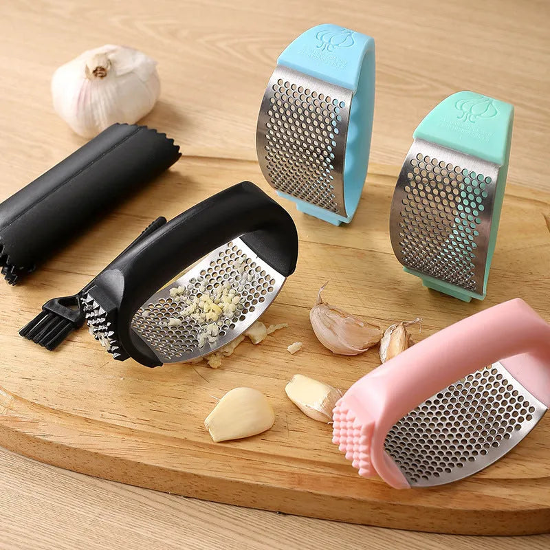 Stainless steel garlic press in green colour with ergonomic handle, measuring 11cm by 7cm on a kitchen counter