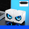 Black and white USB desktop mini speaker with cable next to a laptop computer.