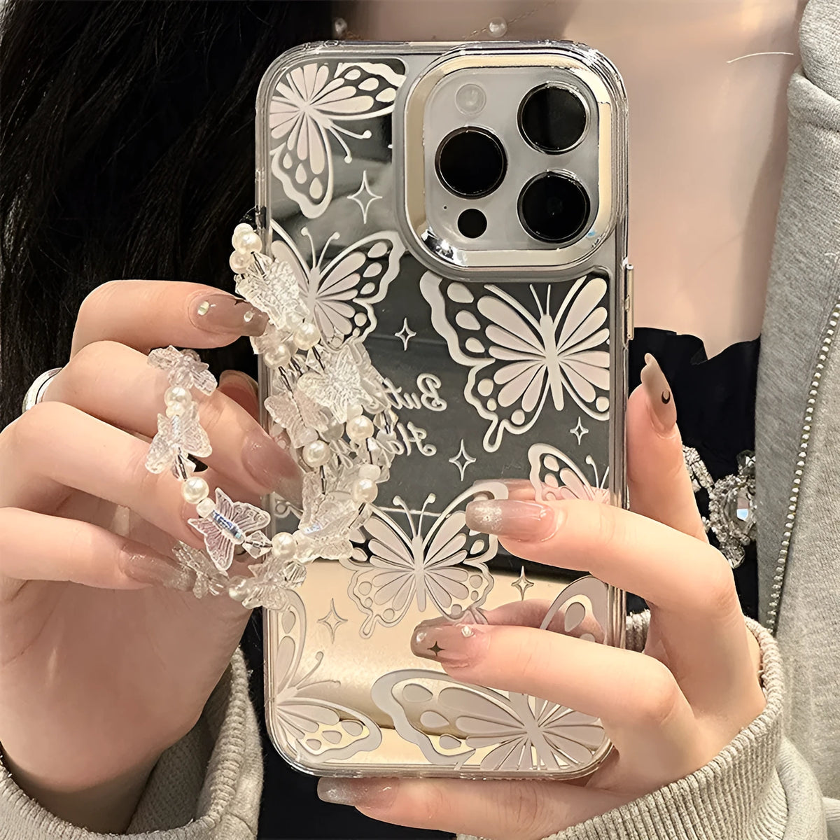 Transparent three-in-one mirror phone case for iPhone with detachable bracelet, showing bow decoration.