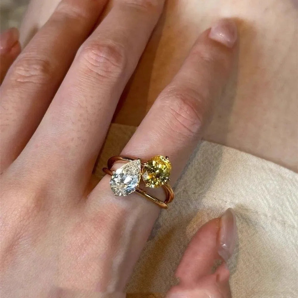 Geometric open copper ring with central water drop double Sheng stone accent on woman's finger