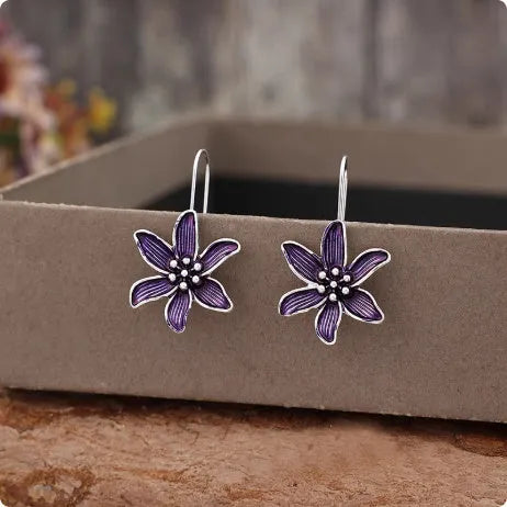 Purple flower-shaped alloy earrings with electroplated finish on white background