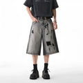 Grey denim shorts with washed finish and hole details, loose fit cropped length