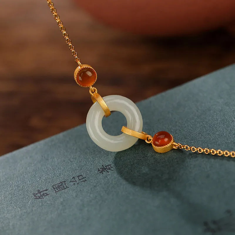 Gold-coloured women's bracelet with a silver base and an inlaid green Hetian jade charm, showing a peace buckle clasp.