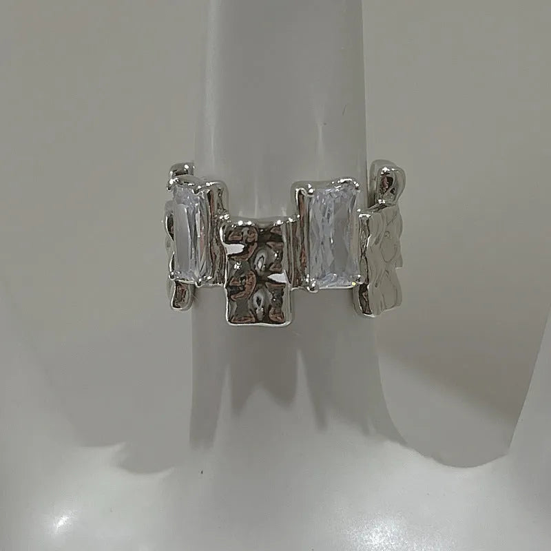 Silver geometric ring with open adjustable band and three-dimensional decoration, shown from multiple angles