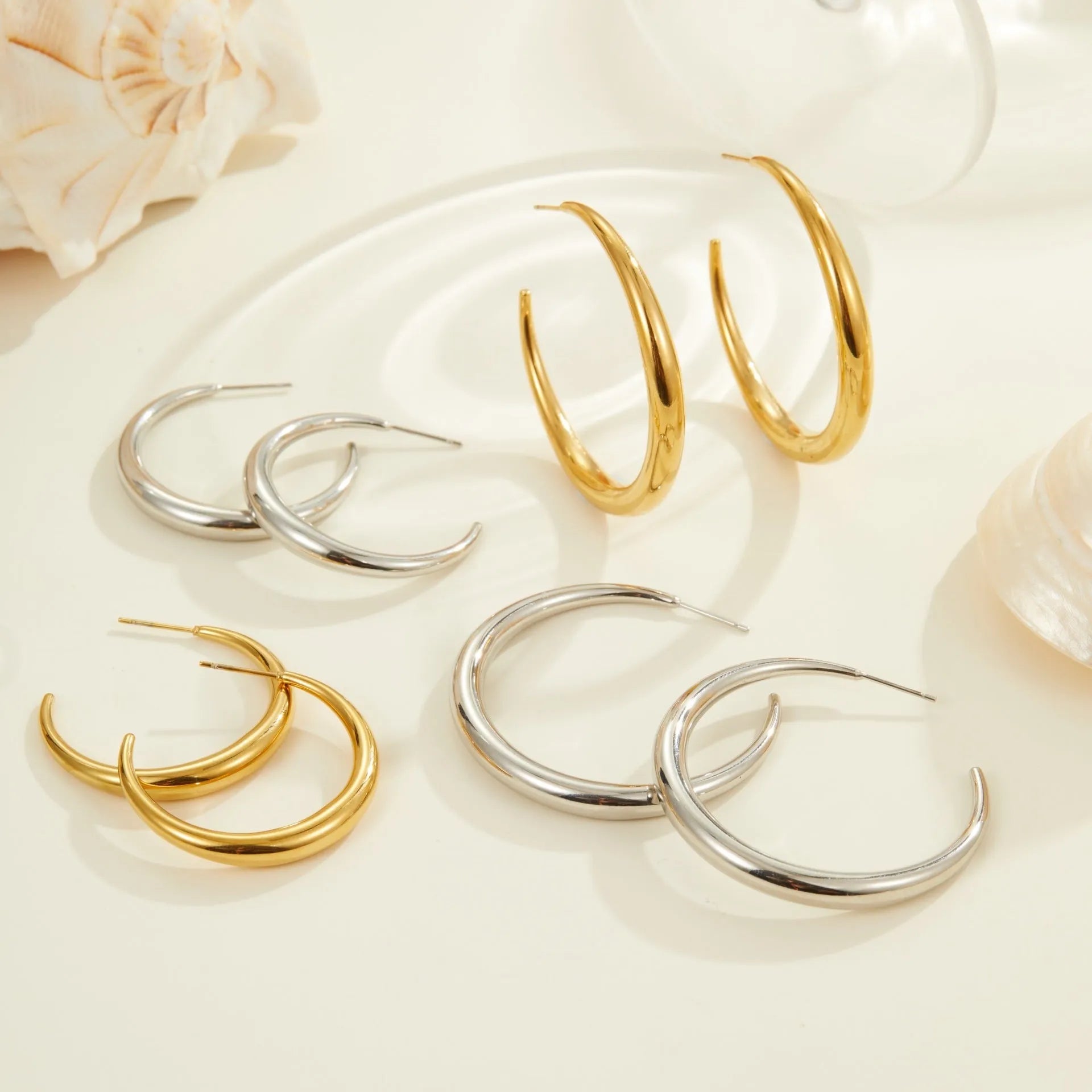 Gold and steel coloured titanium steel hoop earrings for women in large and small sizes.