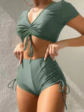 Lady in dark green lace-up bow swimsuit with matching shorts, adjustable front tie.