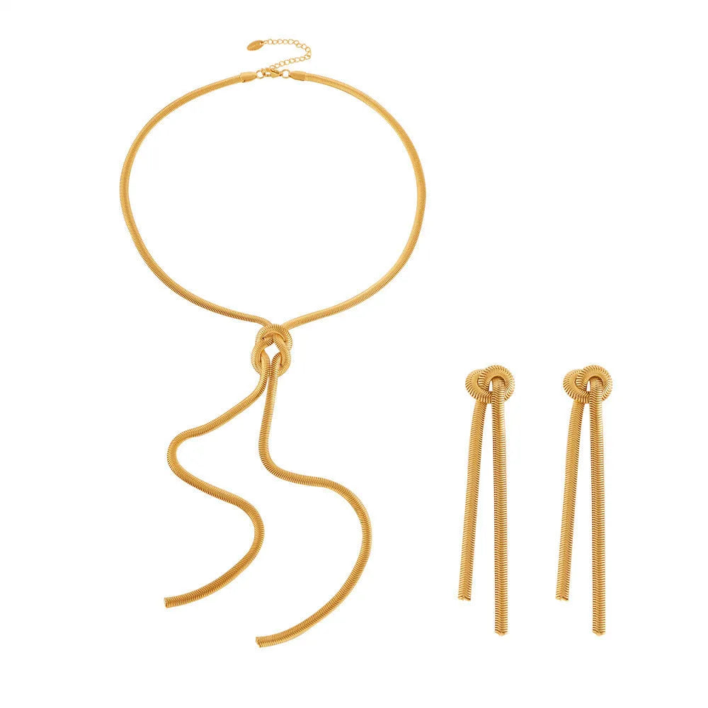 Gold titanium steel necklace with tassel pendant and matching earrings on dark background