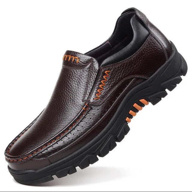 Black and brown leather business casual slip-on shoes with rubber outsoles on wooden floor