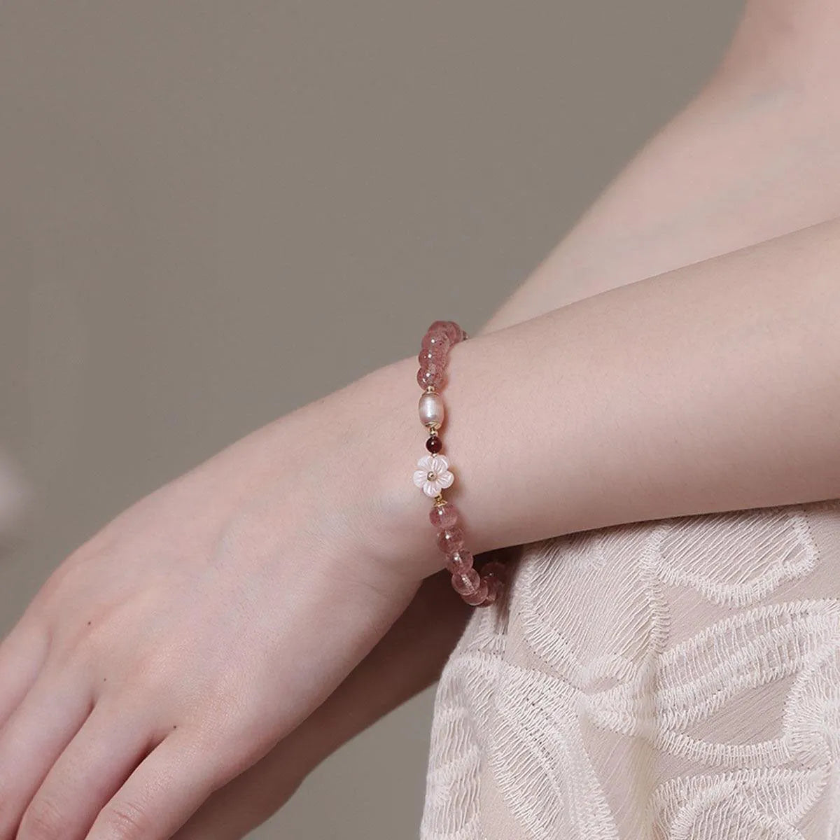 Strawberry quartz crystal bracelet with peach blossom floral design on wrist, showing adjustable 18-20cm length