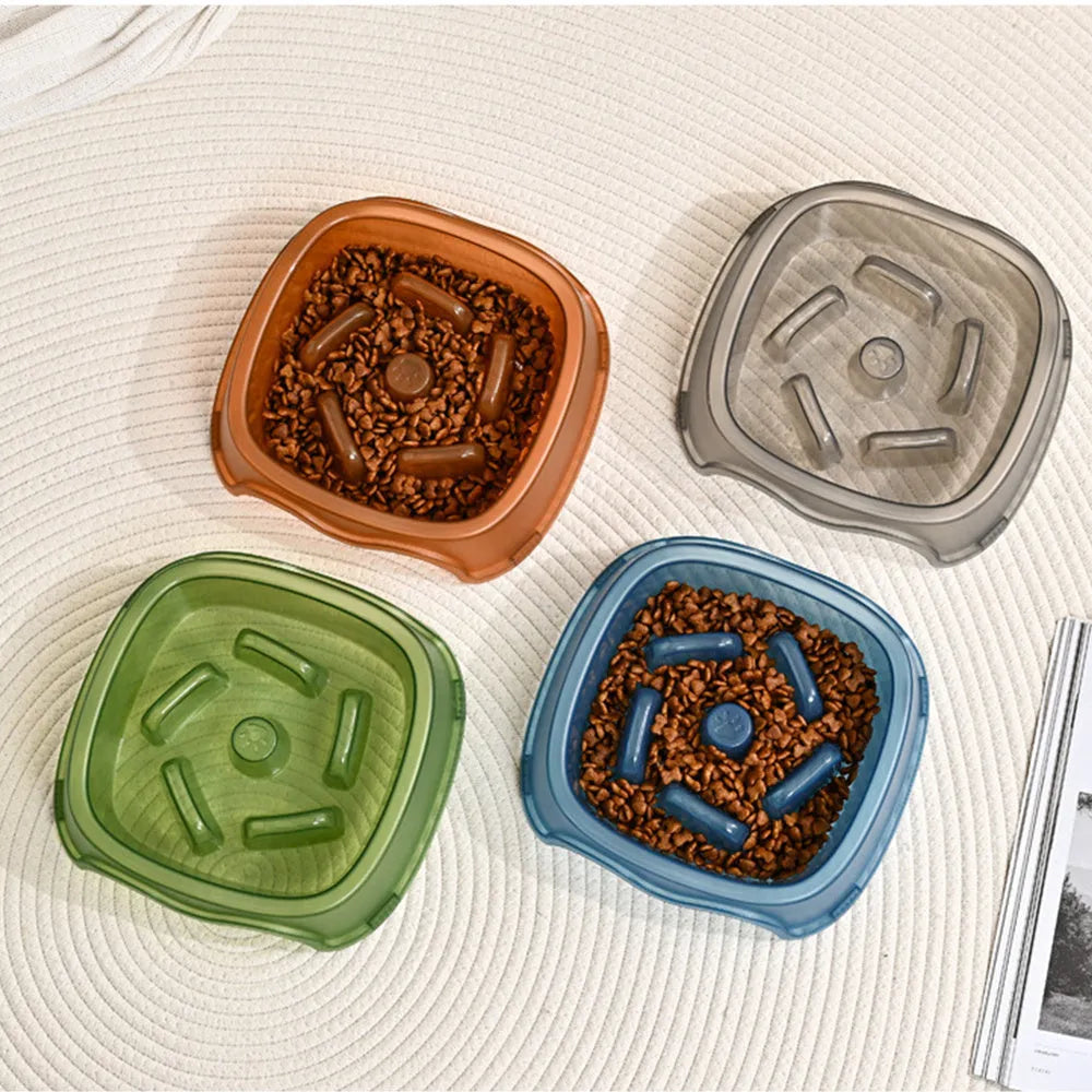 A blue plastic dog slow feeder bowl designed to prevent choking, shown alongside grey, green, and orange colour options.