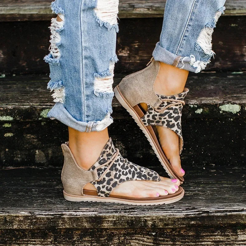 Women's flat sandals with adjustable ankle strap and open toe, shown in multiple colours including black, brown, and leopard print.