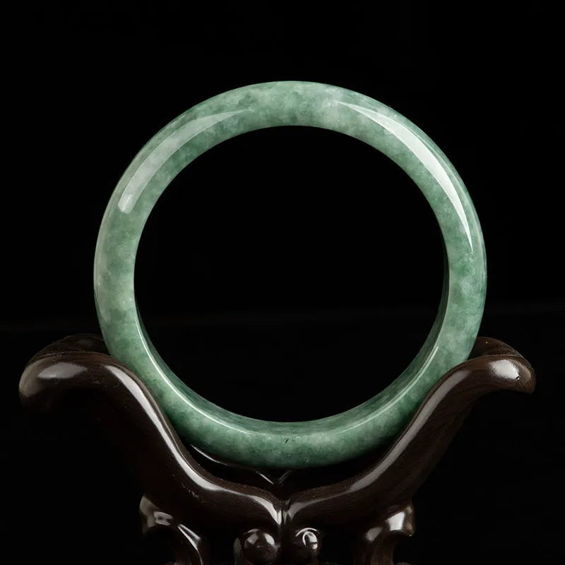 Women's simple bracelet with a natural green emerald bean gemstone on a wrist.