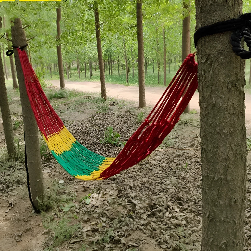Green nylon rope mesh hammock hung between two trees with tying ropes.