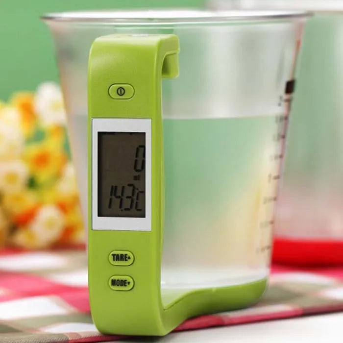 Green electronic scale measuring cup with integrated LCD display showing weight and temperature readings