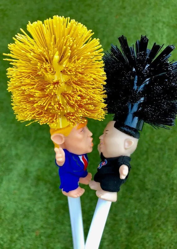 Yellow plastic Trump novelty toilet brush with a hanging slot on the handle.