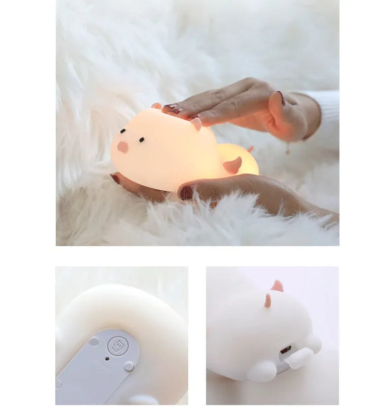 Cute pink silicone pig night light with sleeping design on a bedside table.