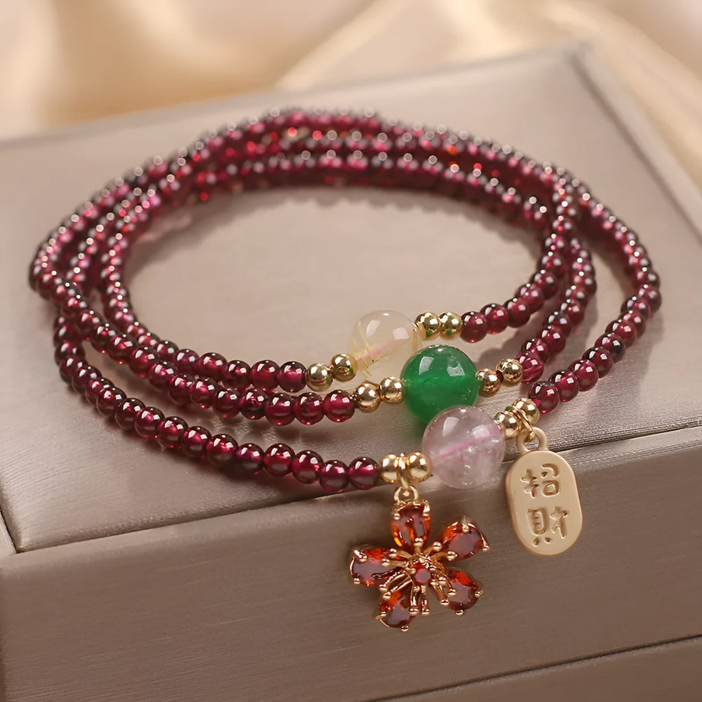 Women's crystal bracelet with pomegranate red cherry blossom beads and sequin details on a simple band.