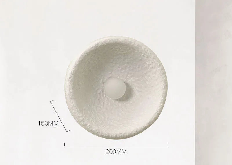 Japanese-style simple white resin wall lamp emitting warm light on a plain wall.