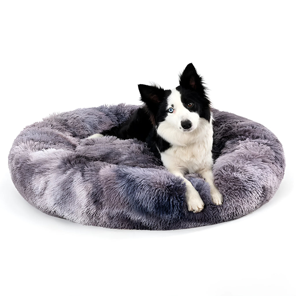 Fluffy donut-shaped dog bed in long plush fabric, shown in a light grey colour with a raised bolster edge.