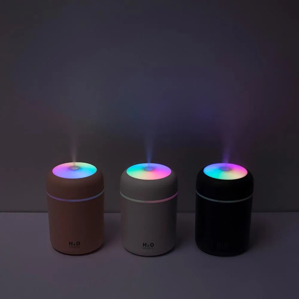 Pink USB mini humidifier with colourful lights on wooden desk