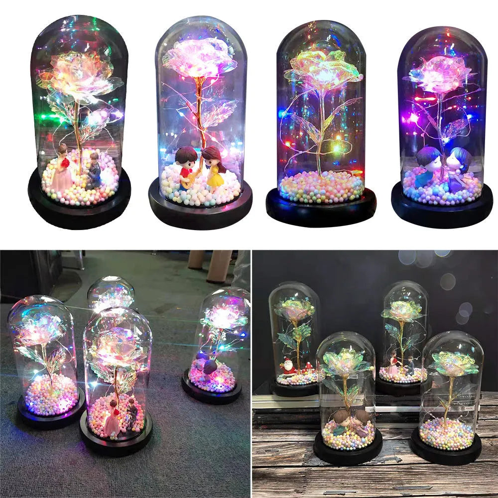 Gold artificial roses inside a clear glass dome ornament with LED lights and decorative accessories.