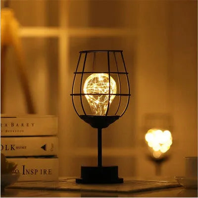 Minimalist hollow iron table lamp in a red wine bottle style with warm white LED light.
