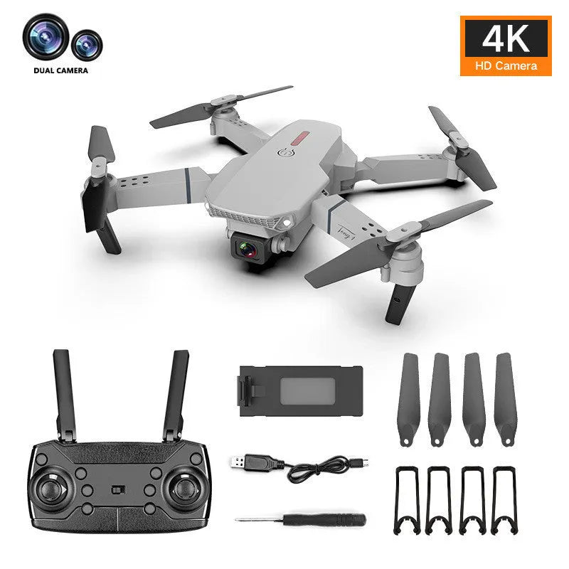 Grey foldable 4K aerial drone with dual cameras and remote control on a grassy field.