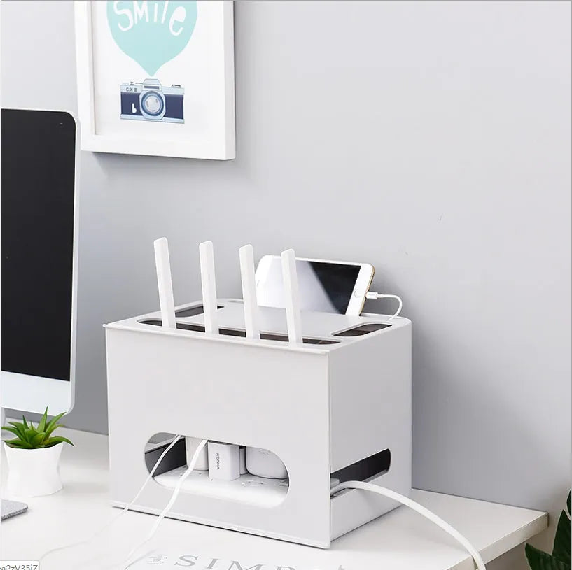 White plastic wireless router storage box mounted on a wall with cables routed through internal channels.