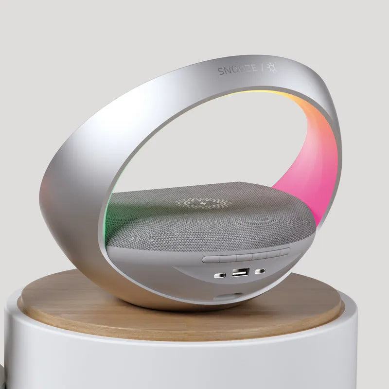 Beige multifunctional wireless charger clock with digital display, fabric speaker grille, and LED wake-up light on a wooden surface.