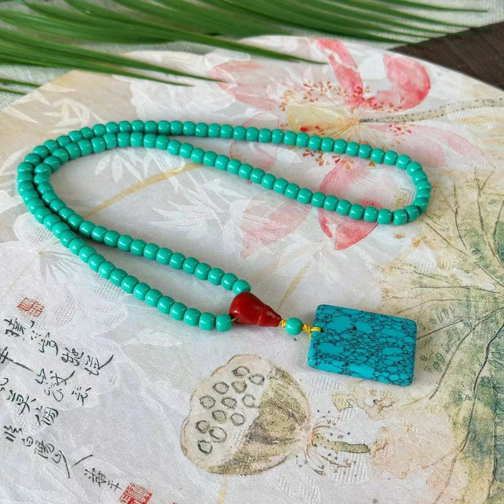 Turquoise mesh flower pendant necklace with adjustable ball bead chain showing hand-woven texture detail