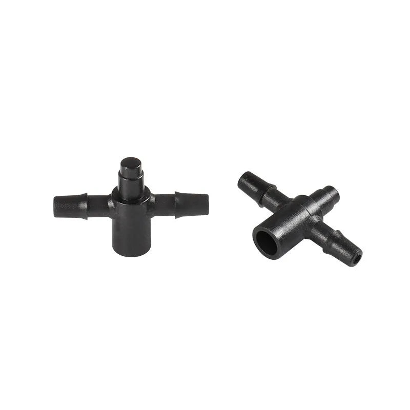 Close-up of a black plastic tee joint water distributor for garden irrigation with three screw-thread outlets.